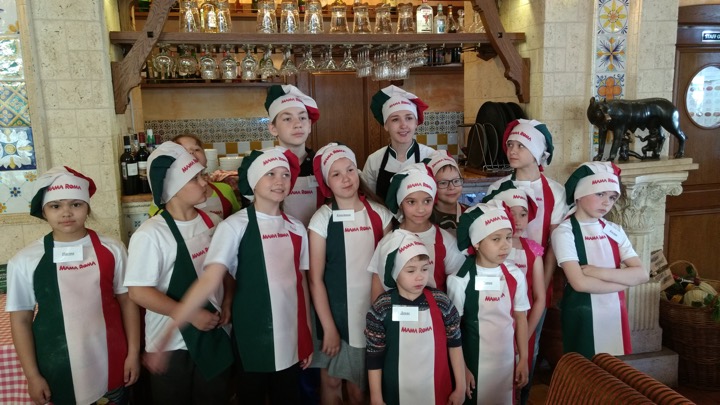The children in their aprons and chef's hats pose for a group picture.