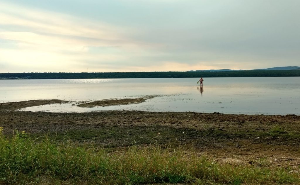 man knee deep in the shallows of a lake