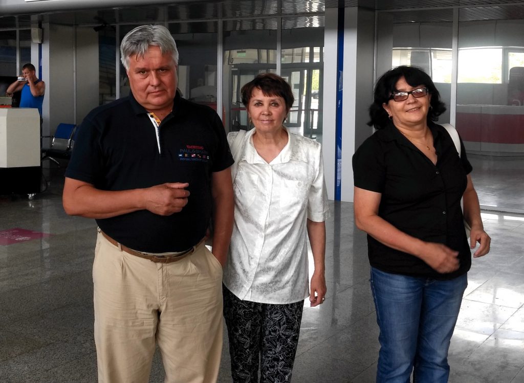 three adults standing for a photo in an airport