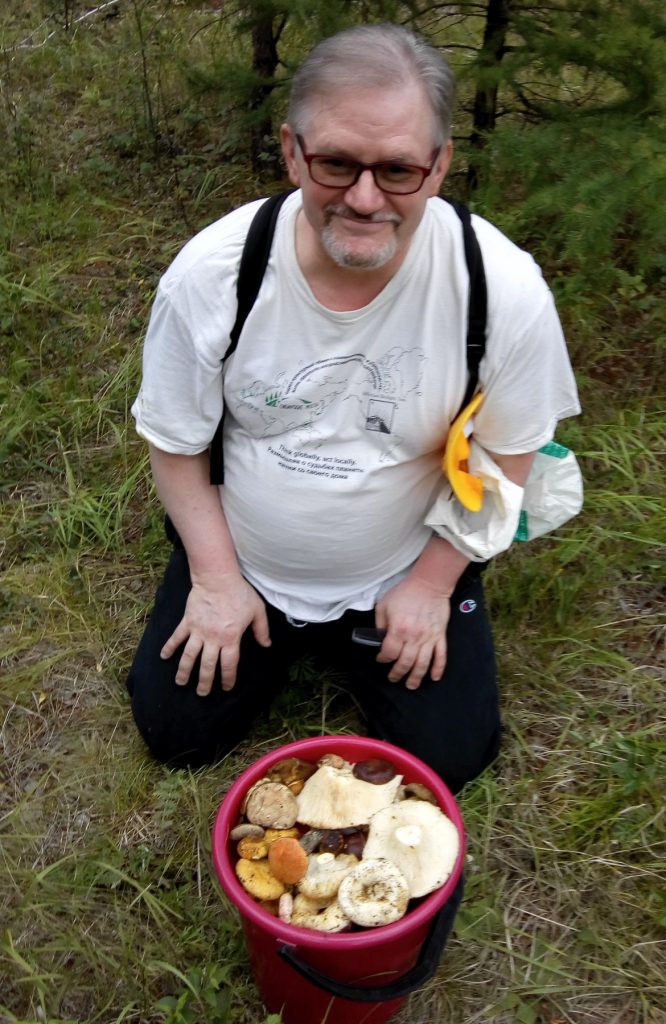 a man crouches behind a bucket of mushrooms