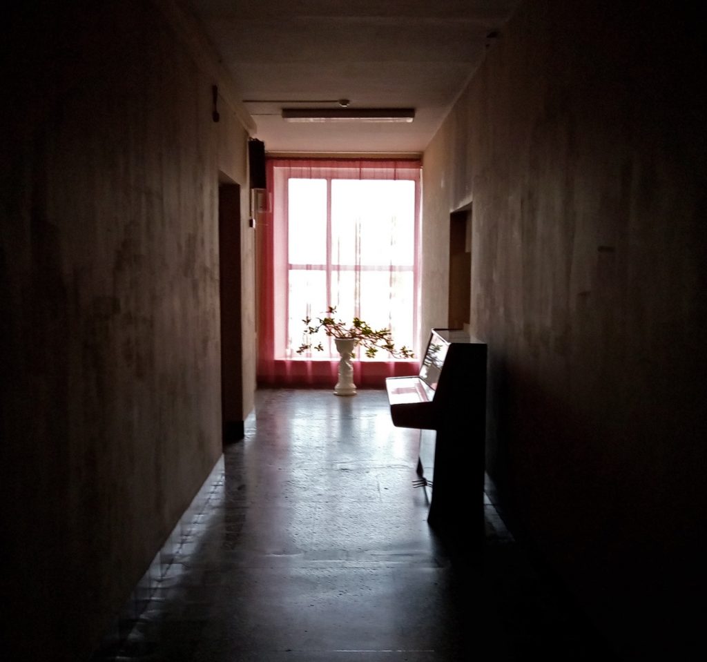 a dark hallway with a little piano and a large vase of flowers, very romantic