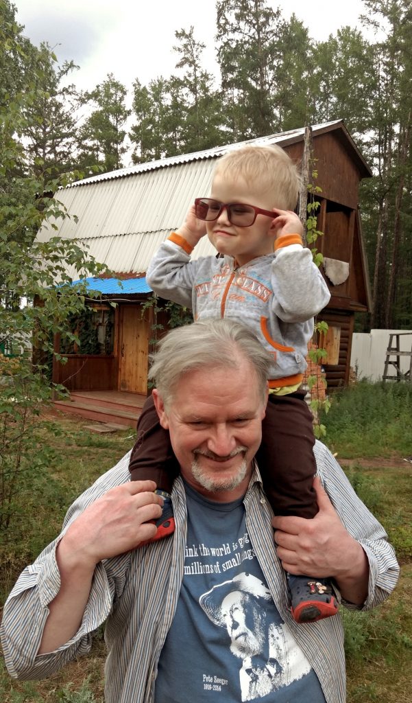 boy on the shoulders of a man and trying on his glasses